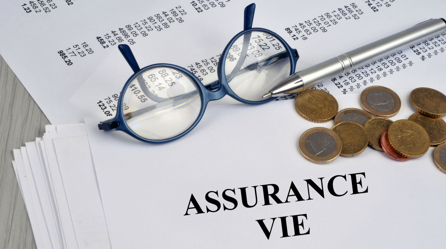 Trois dossiers de couleurs différentes posés sur une table en bois avec une loupe, symbolisant la comparaison et l'analyse de contrats d'assurance-vie.